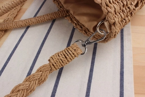 Detail of woven straw bag with silver metal hook and brown fabric lining texture
