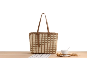 Detail of woven straw tote bag texture with brown leather handles and metal rivets