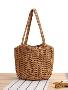 Handmade woven tote bag in khaki rope with long handles on a rustic wooden table