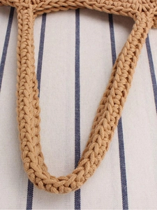 Handcrafted khaki cotton rope bucket bag with detailed woven strap on striped background