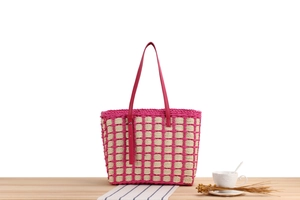 Detail of pink and beige woven checkerboard tote bag with leather straps on a table