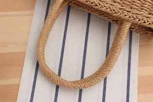 Close-up of the woven texture and spiral handles of the natural paper straw tote bag
