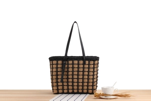 Detail of woven straw tote bag texture with black checkered pattern and leather strap