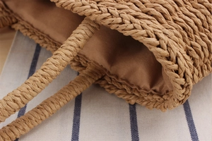 Close-up of handwoven straw bag with natural paper rope texture and brown fabric lining