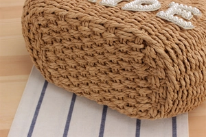 Close-up of hand-woven straw tote bag with pearl and rhinestone letter decorations