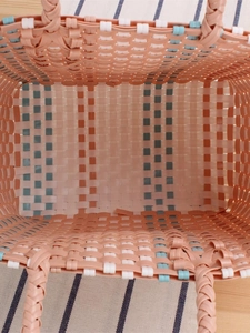 Handwoven plastic picnic basket with pastel pink, orange, and blue contrast stripes