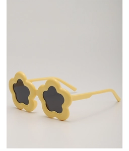 Detail einer gelben Sonnenbrille in Blumenform für Kinder mit dunklen Gläsern vor grauem Grund