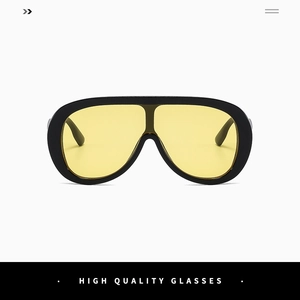 Close-up of oversized yellow shield lens with black frame and metal hinge detail