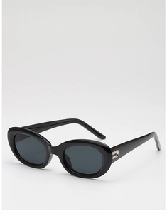 Detail of glossy black oval sunglasses featuring metal hinges and vintage cat eye frame