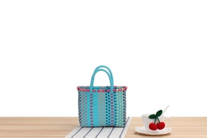 Close-up of handwoven plastic picnic basket with blue, pink and beige vertical stripes