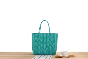 Close-up of turquoise woven tote bag showing wave pattern and sturdy braided handles