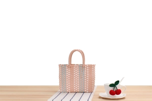 Close-up of pastel pink handwoven picnic basket on a wooden table with soft lighting