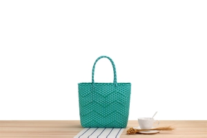 Close-up of green woven tote bag with wavy texture and sturdy handles on a wooden table