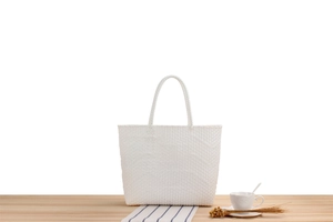 Detail of white woven tote bag showing its intricate grid pattern on a wooden table