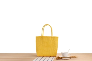 Detailed close-up of a vibrant yellow woven tote bag on a wooden table setting