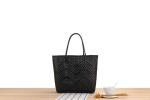 Detailed close-up of large black woven tote bag with distinctive wavy pattern texture