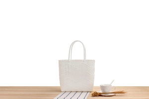 Close-up of white woven tote bag with checkered texture on a minimalist wooden table