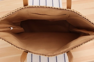 Détail macro du grand sac en paille avec doublure en tissu marron et poche zippée