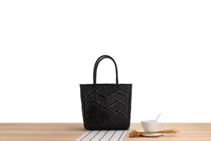 Detail shot of the black woven tote bag showing the textured wave pattern and sturdy handles