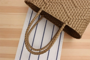 Detail of hand-woven bronze tote bag featuring reinforced braided handles and texture
