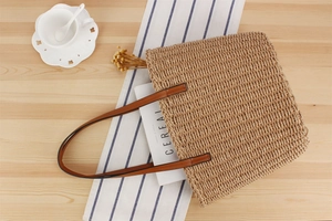 Detailaufnahme der gewebten Strandtasche aus Papierseil mit Lederriemen auf Holztisch