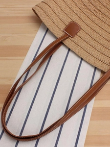 Handmade straw tote bag with brown leather handles on rustic wooden background