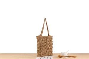 Close-up of intricate crochet knit pattern and soft fabric lining on khaki woven tote bag