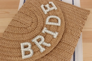 Detail of hand-woven straw clutch featuring pearl and rhinestone BRIDE lettering