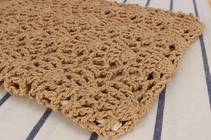 Close-up of retro woven bag with brown crochet hollow pattern and cream fabric lining