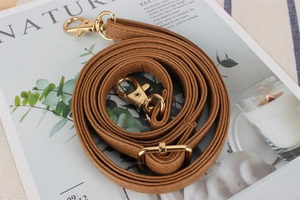 Detail of adjustable brown lychee pattern leather shoulder strap with gold metal buckles
