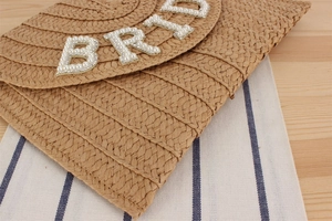 Detailed view of the woven envelope clutch featuring pearl and rhinestone Bride lettering