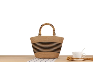 Detail of hand-woven straw tote with bamboo handles and black striped pattern design
