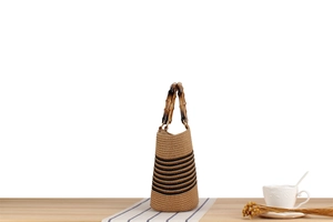 Close-up of woven straw bucket bag with bamboo handle and black striped patterns