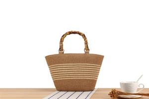 Detail of woven straw handbag featuring bamboo handles and contrast striped texture