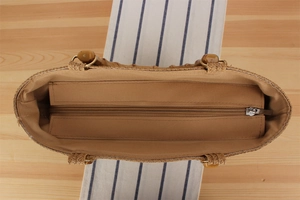Detail of woven straw bag interior with fabric lining and metal zipper closure