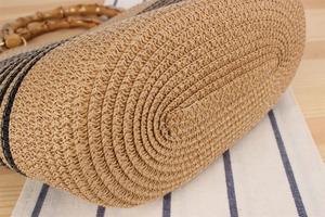 Close-up of handwoven straw bag featuring a bamboo handle and contrast striped pattern