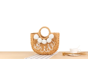 Détail de broderie Bride et pompons blancs sur un sac à main en paille tressée