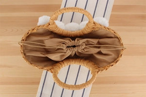 Vue de dessus d'un sac cabas en paille avec pompons blancs et doublure à cordon