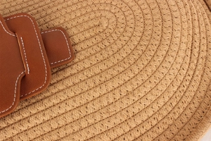 Detailed macro view of woven straw texture with brown leather stitching on handbag