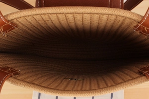 Close-up of woven straw tote bag interior showing natural texture and leather handle