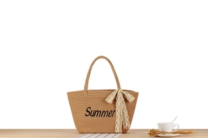 Détail d'un sac de plage tissé beige avec imprimé Summer et nœud en dentelle