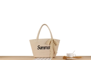Détail du sac cabas en paille beige avec broderie Summer et nœud en dentelle jaune
