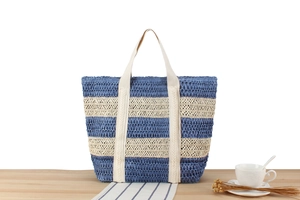Detail of blue and beige woven paper rope tote bag with canvas straps on a wooden table