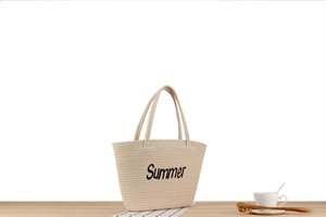Détail du sac seau tissé beige avec broderie Summer posé sur une table en bois