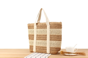 Detailed close-up of two-tone paper rope woven tote bag with canvas straps on a wooden table
