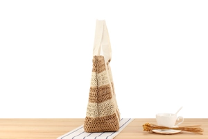 Detail of two-tone woven paper rope tote bag with striped hollow texture and web handles