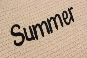 Détail de la broderie Summer sur la texture tissée beige de ce grand sac seau de plage