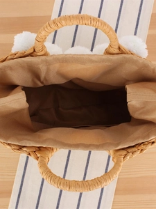 Vue de dessus d'un sac cabas en paille avec pompons blancs et doublure spacieuse