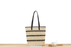 Détail du sac cabas rayé tissé main avec lanières en cuir noir sur surface boisée