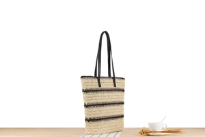 Détail du grand sac cabas tissé avec rayures noires sur une table en bois rustique